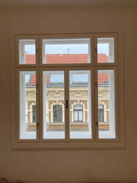 Zwei große rechteckige Fenster nebeneinander in einem Raum mit Holzwänden